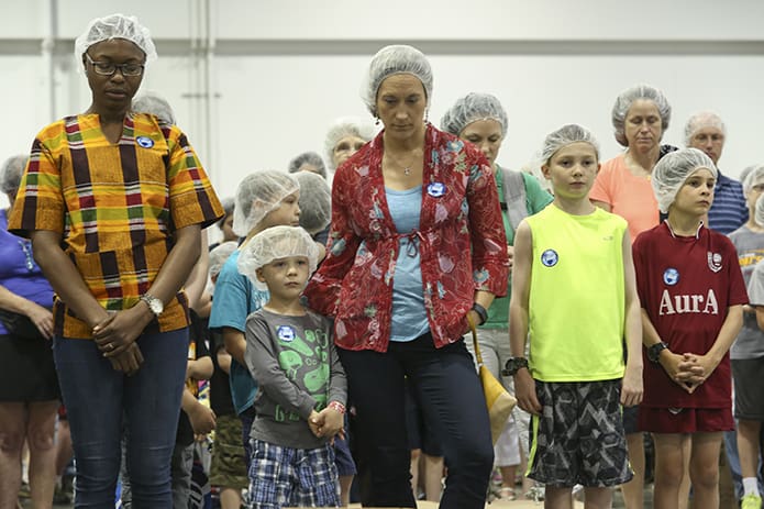 (L-r) Adesuwa Inneh of St. Philip Benizi Church, Jonesboro, Vander Stelten, 5, his mother Erica of St. Thomas More Church, Decatur, Liam Viets, 11, and his brother Colin, 9, of Transfiguration Church, Marietta, stand with 295 other volunteers as Father Victor Galier, pastor of St. Anthony of Padua Church, Atlanta, leads the group in a prayer before the second session of Starve Wars gets underway. Photo By Michael Alexander