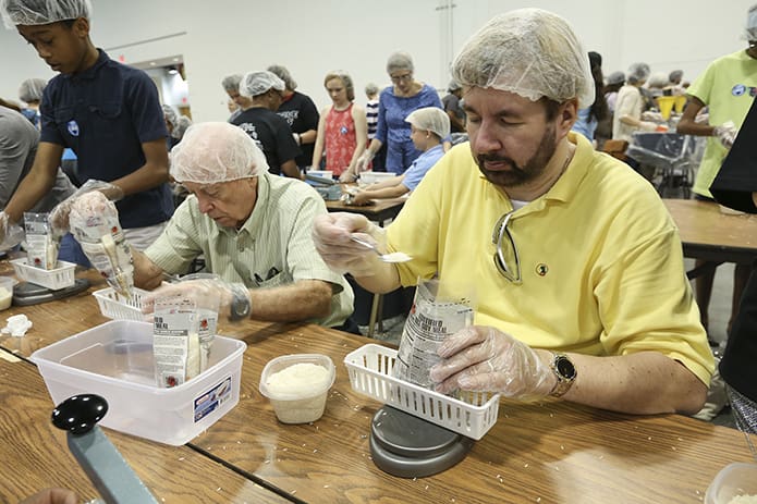 Jim Hughes, left, of All Saints Church, Dunwoody, and Paul Nieuwstadt of St. Matthew Church, Winder, weigh the meal bags to ensure they fall between 389 and 394 grams. Photo By Michael Alexander