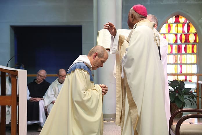 Abbot-elect Augustine Myslinski, OCSO, kneels before Archbishop Wilton D. Gregory during the prayer of blessing. At the conclusion of the prayer he officially assumes the role and title of abbot. Photo By Michael Alexander