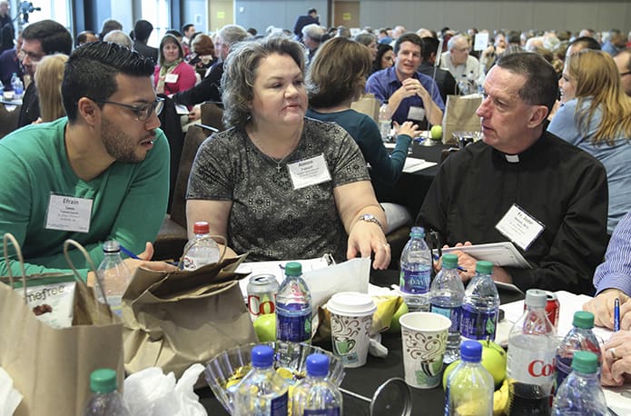 Parish council member Efrain Tores of St. Oliver Punkett Church, Snellville, the parish director of elementary religious education Aimee Tolmich, and their La Salette pastor Father John Welch participate in a table discussion during the March 14 session of the Amazing Parish conference at the Atlanta Marriott Marquis Hotel. Photo By Michael Alexander