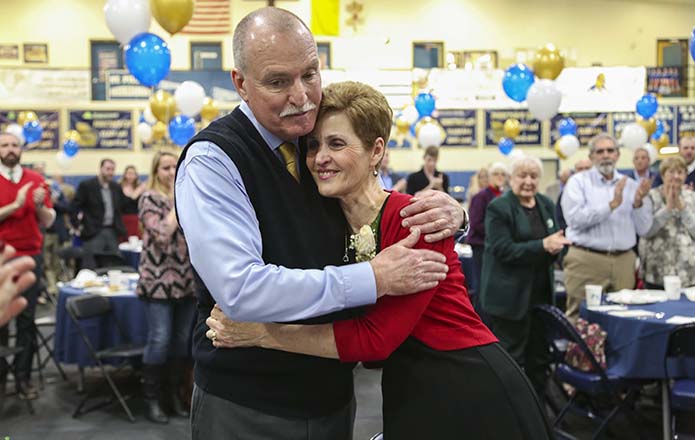After concluding the speech during his Dec. 18 retirement luncheon in the St. Pius X High School gymnasium, Mark Kelly steps off the stage into the arms of his wife of nearly 40 years, Linda. Kelly worked at the Atlanta school for 42 years. For 31 of those years he was the athletic director. Photo By Michael Alexander