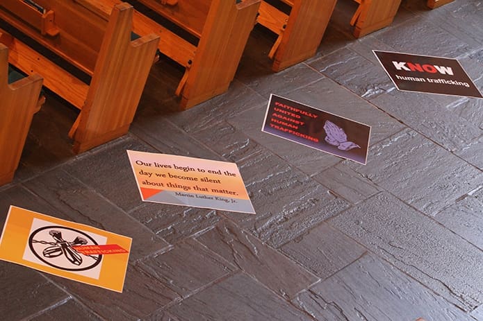 Posters line the center aisle at St. Philip Benizi Church in Jonesboro. The first 60 minutes, of a five-hour prayer service during Atlanta Prays, focused on ending human trafficking. St. Philip Benizi was an outside the perimeter host site for the south side of the city on May 6, the third day of 125 Hours of Prayer. Photo By Michael Alexander