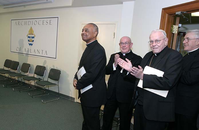 When Archbishop Wilton D. Gregory, far left, arrived for the Dec. 9, 2004 press conference announcing him the sixth archbishop of Atlanta, he was accompanied by (l-r) Msgr. R. Donald Kiernan, vicar-general/pastoral ministries, Archbishop John F. Donoghue and Msgr. Paul Reynolds, vicar-general in curia/chancellor. Photo By Michael Alexander