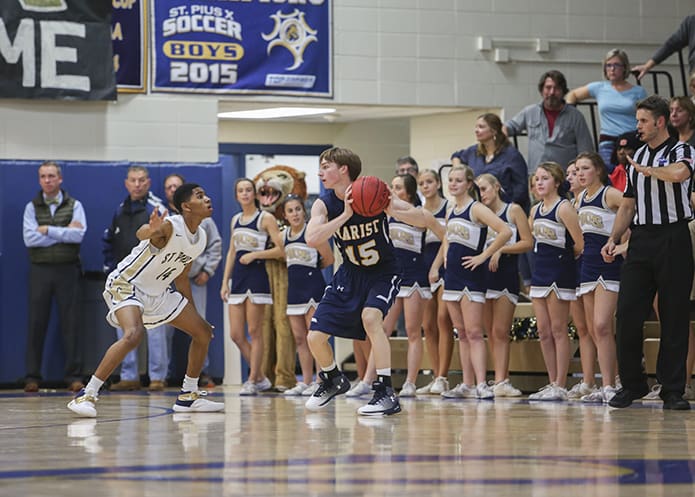St. Pius X junior guard Troy Stephens (#14) defends Marist School senior shooting guard Chris Dick (#15) during the second period of the Dec. 6 basketball game at the St. Pius gymnasium. On offense Stephens scored 10 points to help his team defeat Marist 52-41. Photo By Michael Alexander