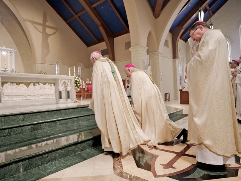 Archbishop-emeritus of New Orleans Alfred C. Hughes, left, and Archbishop of New Orleans Gregory M. Aymond, right, bow before the altar during the opening procession of the ordination of Bishop John Nhan Tran, who served in  Louisiana for three decades. Archbishop Christophe Pierre, apostolic nuncio, follows. Photo by Johnathon Kelso