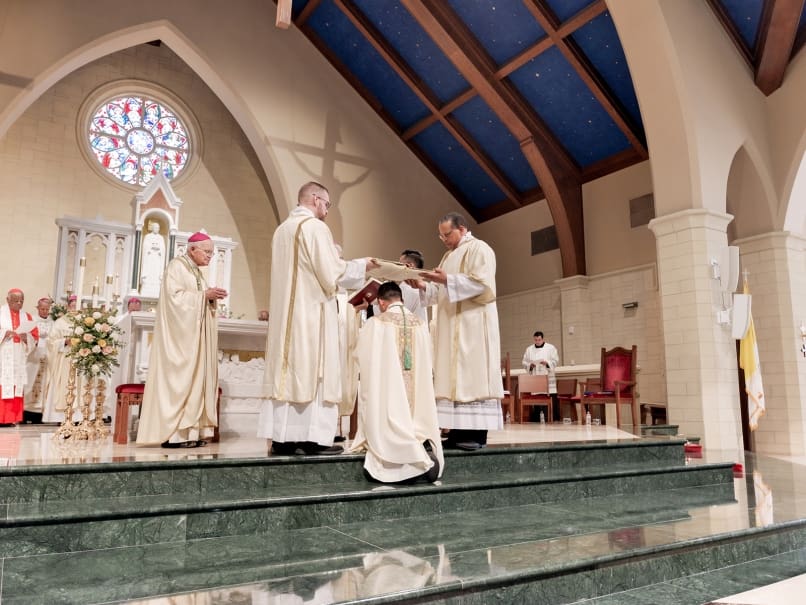 Deacons hold the Book of Gospels over the head of His Excellency The Most Reverend John Nhàn Tran during the Episcopal Ordination at Saint Peter Chanel Church. Photo by Johnathon Kelso