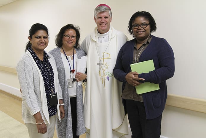 Bishop Ned Shlesinger poses for a photo with Atlanta Veterans Administration Medical Center education team members (l-r) Saly Pius, Debbie Combs and Anne Cadet following the Oct. 2 Mass in the hospital chapel. Photo By Michael Alexander