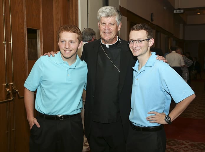During the reception that followed the July 18 vespers service, Bishop-designate Bernard E. (Ned) Shlesinger III, center, poses for a photo with his godsons, Cameron, left, and James Giddens. The teens made the trip from Newton Grove, N.C. with their parents Wade and Janice. When Bishop-designate Shlesinger was Father Shlesinger, he conducted their parents’ wedding on October 19, 1996. Photo By Michael Alexander