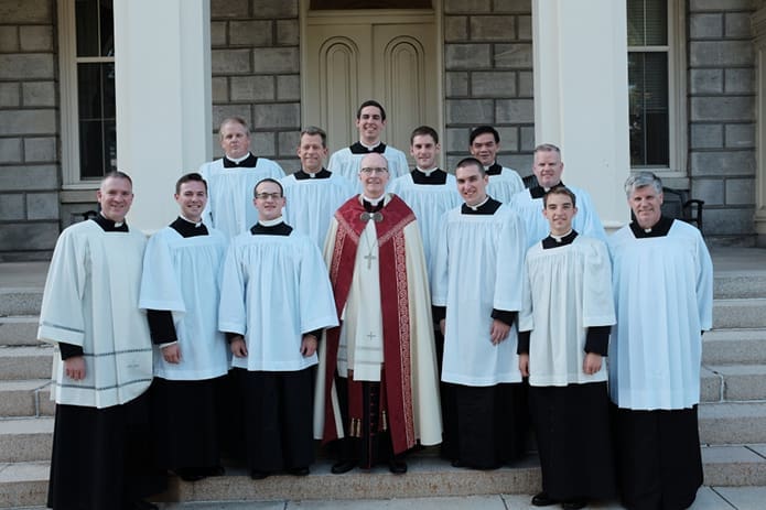 Father Bernard E. (Ned) Shlesinger III, bottom, far right, stands with Bishop Timothy Senior, center, rector of Saint Charles Borromeo Seminary, Wynnewood, Pa., and Father Brian Kane, bottom, far left, dean of men for the seminary’s theology division, stand with new seminarians in the Theology Seminary during Cassock Day in the fall of 2015. At the time Father Shlesinger was spiritual director for the seminary’s theology division. Photo Courtesy of Saint Charles Borromeo Seminary