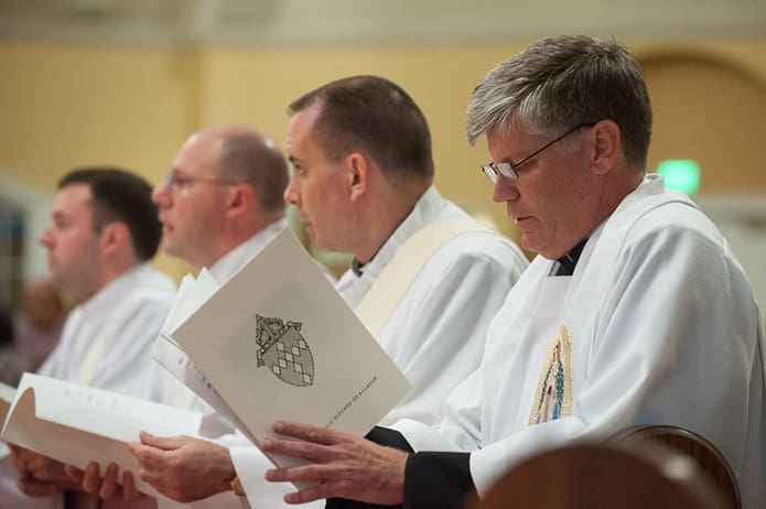 In this 2013 photo Father Bernard E. (Ned) Shlesinger III, far right, attends the June 1 priestly ordination for (l-r) Ryan Elder, Nicholas Cottrill and Thomas Duggan at St. Michael the Archangel Church in Cary, N.C., when he was the Diocese of Raleigh's director of vocations and seminarian formation. Photo Courtesy of the Diocese of Raleigh