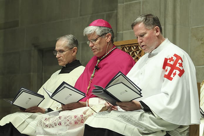 Jesuit Father Brendan Lally, left, of St. Joseph University, Philadelphia, Pa., and Father James F. Garneau, Ph.D., right, director of the Office of the Permanent Diaconate for the Diocese of Raleigh, join Bishop-designate Bernard E. (Ned) Shlesinger III on the altar during solemn vespers. Photo By Michael Alexander