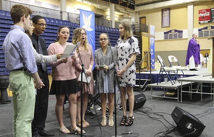 The Marist Singers, (l-r) Sam Costantino, Lili Amirhosseini, Jacob Conley, Natalie Selover, Allison Hart, Francesca Herrera, and Caroline Elledge sing the Irish Blessing (“May the Road Rise to Meet You”) for Bishop-designate Joel M. Konzen, SM, as he stands on the altar in the background. Photo By Michael Alexander