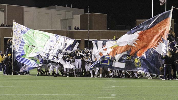 Marist School War Eagle football players bust through the banner before they clash with the Titans of Blessed Trinity High School, Roswell. Photo By Michael Alexander