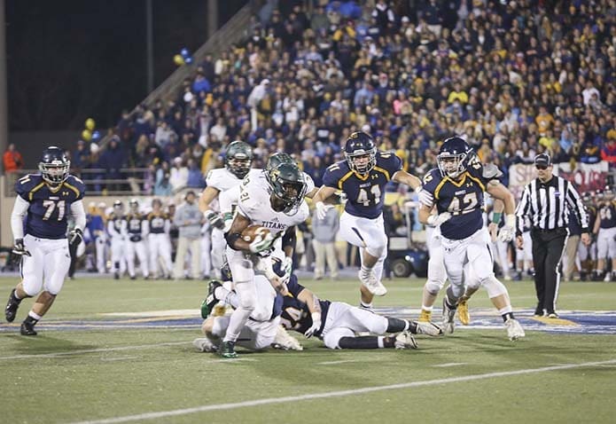 Blessed Trinity High School’s Elijah Green (#21) is pursued by Marist School outside linebacker Joseph McDermond (#41) and middle linebacker Colby Belland (#42) during a second quarter run. Green rushed for 86 yards on 15 carries as Blessed Trinity beat Marist 16-7 to capture its first state football championship. Photo By Michael Alexander