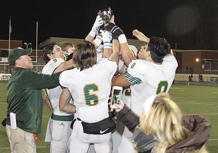 A fan captures the moment on her smartphone as Blessed Trinity High School head football coach, Tim McFarlin, far left, hands off the championship trophy to a host of players, including quarterback Jake Smith (#9), wide receiver Ryan Davis (#6) and defensive tackle JR Bevins (#8). Photo By Michael Alexander
