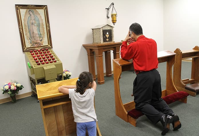 A man and child kneel in the Blessed Sacrament chapel following the Sept. 13 Mass of dedication. Photo By Michael Alexander
