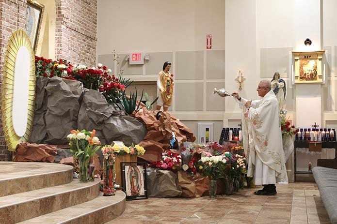 Father Carlos Arturo Quintero, administrator of Divino Niño Jesús Mission, censes the shrine of Our Lady of Guadalupe, at the beginning of the Dec. 12 evening Mass. Photo By Michael Alexander
