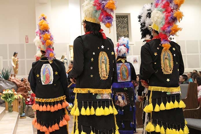 Bearing images of Our Lady of Guadalupe on the back of their jackets, members of Grupo de Danza Folklorica Mexicana Tonalli of Athens dance in the direction of the shrine to the Blessed Virgin. Photo By Michael Alexander