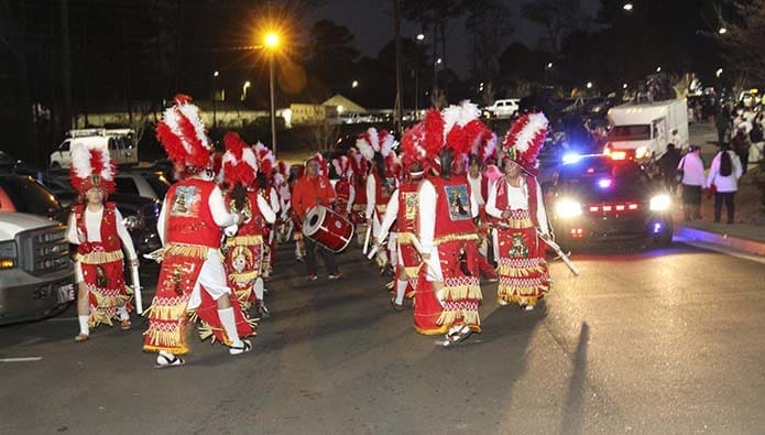 A Clayton County police cruiser pulls up alongside members of the San Felipe de Jesus Mission dance troupe from Forest Park. Both were preparing to lead a crowd of several hundred people in a two-mile procession, Dec. 11, from the mission through the community in honor of Our Lady of Guadalupe on the eve her feast day. Photo By Michael Alexander
