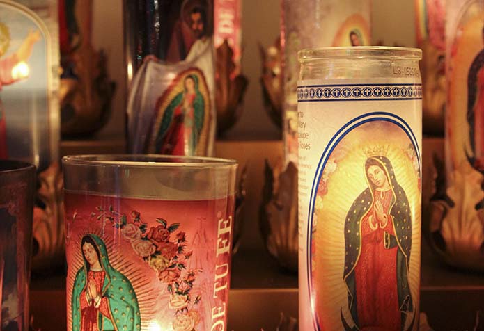 Throughout the evening people brought Our Lady of Guadalupe votive candles, which were placed on a stand to the side of the main altar at San Felipe de Jesús Mission in Forest Park. Photo By Michael Alexander