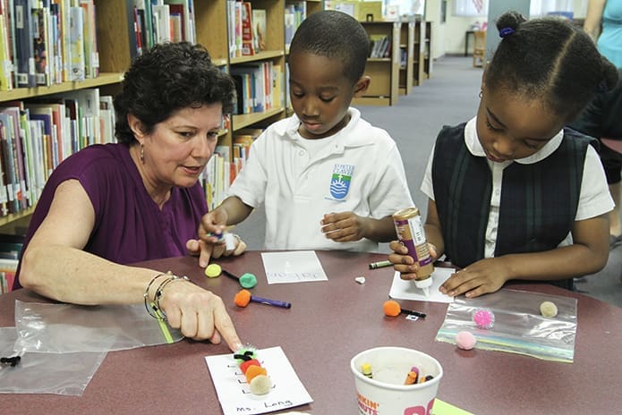 Casey Long, president of the Christ Child Society of Atlanta, works with pre-kindergarten students in late April as they work on an arts and crafts project that involved making a caterpillar. Photo By Michael Alexander