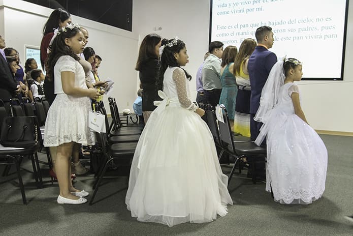 Standing with their respective families, (l-r) Ashley Molina, 11, Natalia Meneses, 10 and Camila Juarez, 8, were three of the 42 children making their first Holy Communion during a 6 p.m. liturgy at the mission on May 19. Photo By Michael Alexander