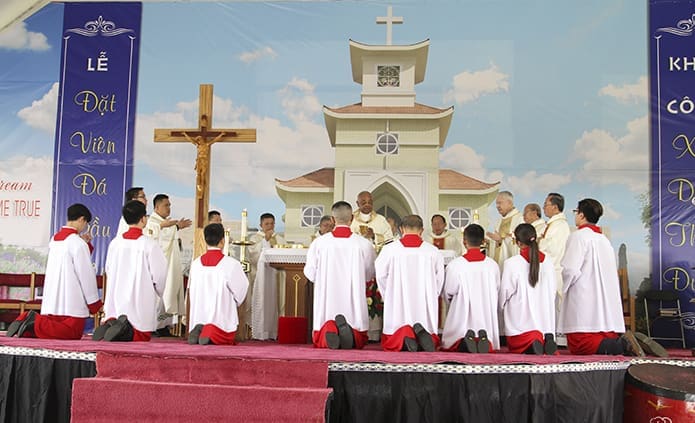 With a backdrop displaying an image of the proposed Holy Vietnamese Martyrs Church, altar servers kneel before the altar as Archbishop Wilton D. Gregory conducts the consecration during the Liturgy of the Eucharist Aug. 27. After the Mass, Archbishop Gregory participated in a formal groundbreaking with the pastor, Father Francis Tuan Tran, and a host of others. Photo By Michael Alexander