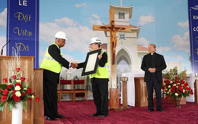 Archbishop Wilton D. Gregory, far left, shakes the hand of Holy Vietnamese Martyrs Church pastor Father Francis Tuan Tran after presenting a framed proclamation from the Archdiocese of Atlanta to him. Photo By Michael Alexander