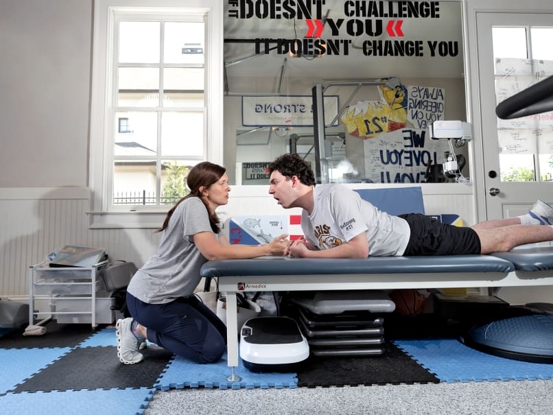 Devon Corbett works at his home gym with his occupational therapist Claire Cherry of Strength Within Therapy. The Marist School student was injured in a 2020 ski accident. Photo by Johnathon Kelso
