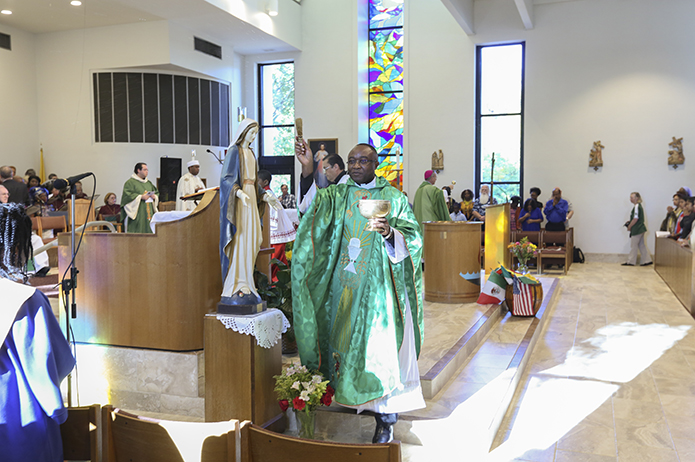 During the Oct. 23 rededication Mass Father Paschal Amagba, pastor of Corpus Christi Church, Stone Mountain, blesses the congregation and the walls on one side of the church, while Bishop Luis Zarama, background, does the other side. Photo By Michael Alexander