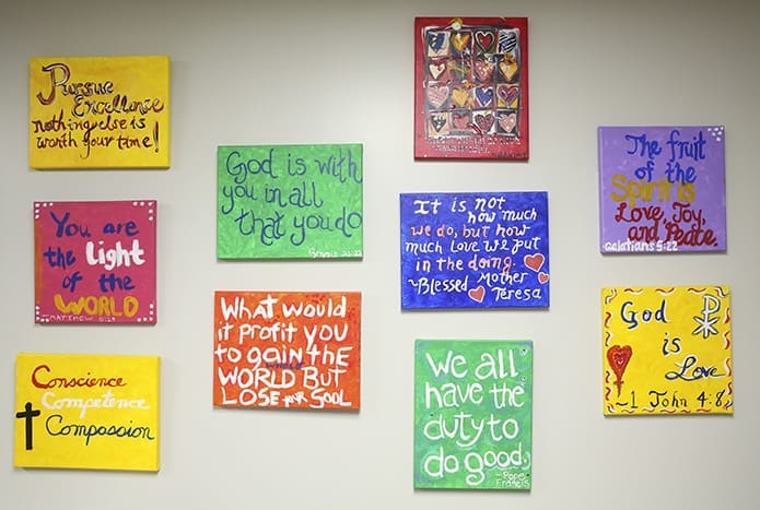 Handmade plaques created by Cristo Rey Atlanta students, bearing Scripture or inspirational messages, are prominently displayed on the school’s administrative floor, opposite the elevators. Photo By Michael Alexander