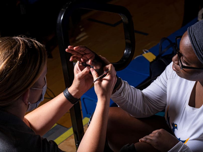 Sadajia Stewart (#23) of The Cristo Rey Flames has her hand checked by a medical trainer during the game against Notre Dame Academy. Photo by Johnathon Kelso