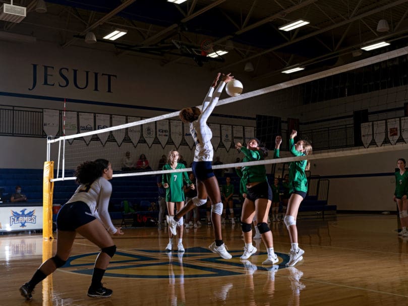 Peyton Davie (#12) of The Cristo Rey Flames,hits a kill shot over Notre Dame Academy.  The Flames claimed victory in the Sept. 23 game after five sets of play. Photo by Johnathon Kelso