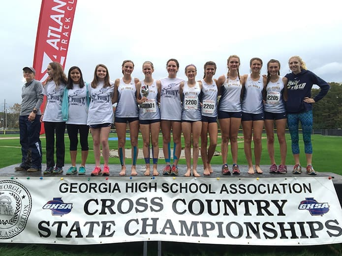 Coach Debbie Guilbeau, far left, and the St. Pius X High School girls cross-country team stand on the podium with their second place trophy following the Class AAAA state championship meet. It was the third consecutive state runner-up finish for the school. In a field of 211 runners St. Pius freshman Ellie Glenn (#2200) came in first.