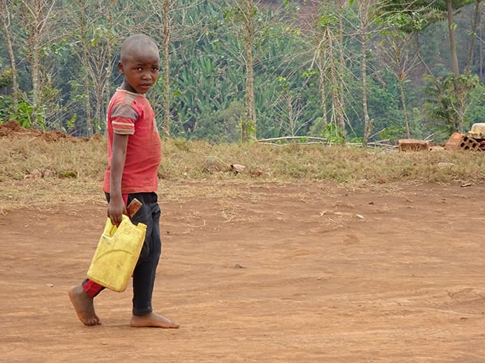 A Rwandan boy carries clean water near the diocesan spirituality center in Cyangugu.