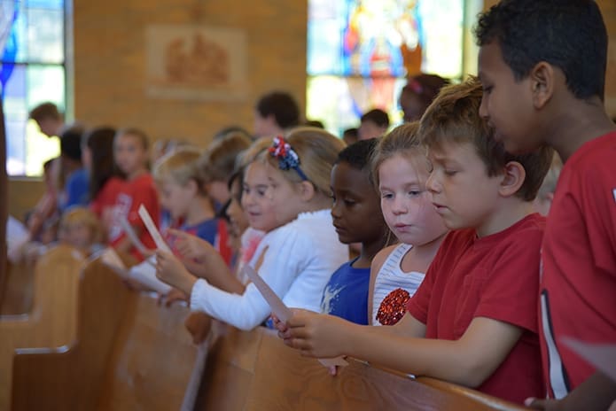 St. Thomas More School second-graders pray for peace on Sept. 9 with the rest of the congregation.