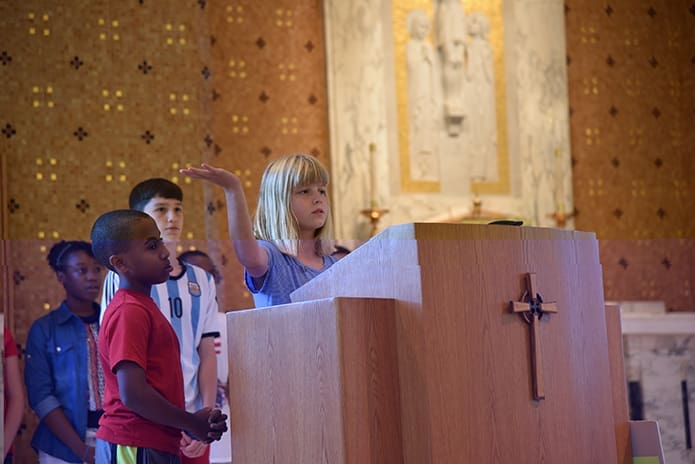 (Front to back) St. Thomas More fourth-grader Libbie Brownlow leads an intercessory prayer for peace as Musse Woldu, Santi Bondulich and Justine Johnson wait their turn to do the same.