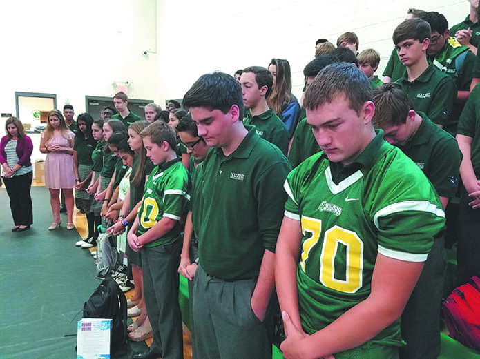 (R-l) Holy Spirit Prep School students Connor McKittrick, Benjamin Ambo and Gavin Marshall follow Upper School principal Jocelyn Sotomayor in praying for peace on Sept. 9. Holy Spirit Prep’s high school assembled together in the gym for their prayer. The Lower School prayed a decade of the rosary together led by fifth- and sixth-graders, directed by Lower School Principal Peter Schultz.