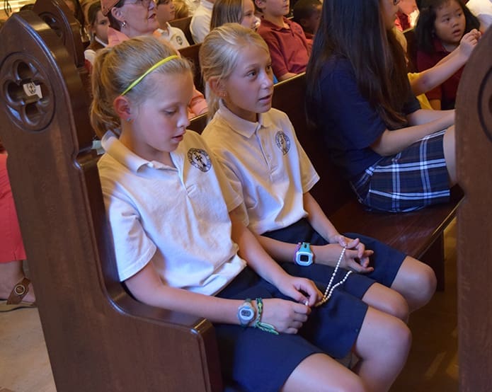 Our Lady of the Assumption School, Atlanta, fifth-grader Libby O’Donnell, left, and fourth-grader Ella Stone share a rosary as they pray together on the Day of Prayer for Peace.