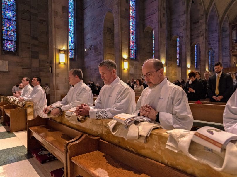 Deacons gather together to pray at the altar rail during the ordination Mass.  Photo by Johnathon Kelso