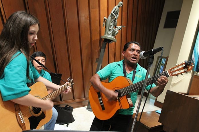 (L-r) Guadalupe Pedraza, 14, and percussionist Emmanuel Perez, 13, play beside choir director Martin Torres. He formed the choir in 2011. Photo By Michael Alexander