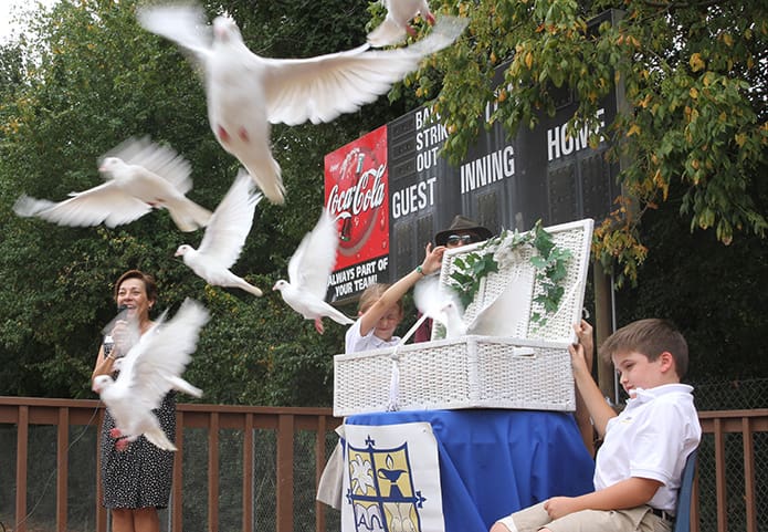 Immaculate Heart of Mary School fourth-grader Grace Sheehy and her brother Will, a third-grader, release some 20 doves from a basket to the surprise of all during the final installment of the school’s symbolic welcome of Pope Francis to the United States. Watching from the side is director of Faith Formation Carmen Graciaa. Photo By Michael Alexander