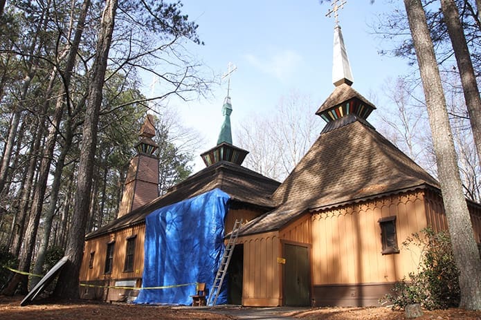 A blue tarp covers the side of Epiphany Byzantine Catholic Church, Roswell, where it incurred damage from an arson fire. The wooden church, marked by its Carpathian architecture style, was the first Byzantine Catholic Church in Georgia when it was dedicated in 1982. Photo By Michael Alexander