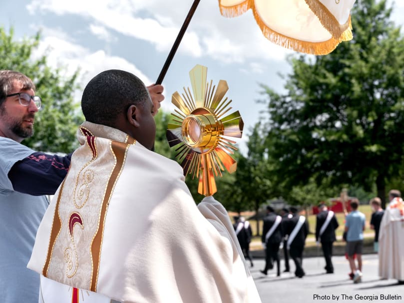 Father Valery Akoh of St.  Matthew Church, Tyrone, carries the Blessed Sacrament during the Eucharistic Pilgrimage stop at St. Mary's Academy in Fayetteville. Photo by Johnathon Kelso