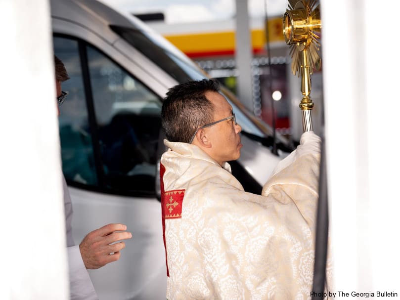 Bishop John N. Tran processes with the Blessed Sacrament through a Shell Gas Station along the way to Our Lady of Vietnam church in Riverdale. Photo by Johnathon Kelso