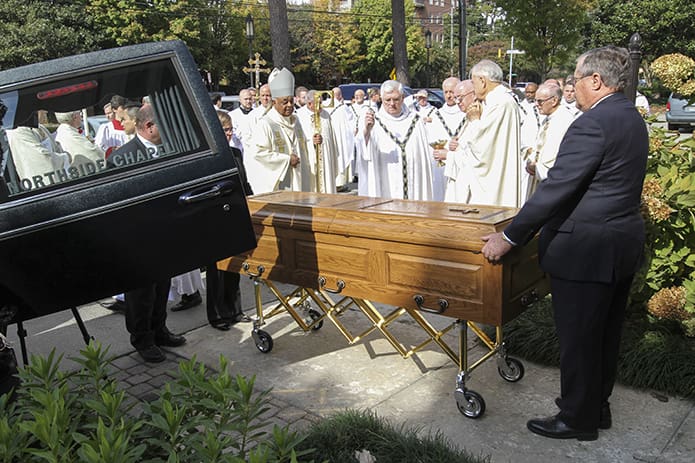 Father John Murphy, the pastor of Holy Trinity Church, Peachtree City, sprinkles holy water over the coffin of his brother priest and fellow Irishman, the late Father Edward O’Connor, just before it is placed into the funeral hearse. Photo By Michael Alexander