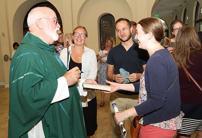 Following the Aug. 21 evening Mass at St. Thomas More Church, Decatur, (counter-clockwise, from left) Jesuit Father Gregory Boyle returns Jillian Madden’s copy of his book, “Tattoos on the Heart,” to her after signing it. Looking on are her friends Nicholas Arjona and Julianne Green. Madden and Green served as Jesuit volunteers in Atlanta from 2013-2014. Photo By Michael Alexander