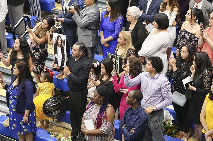 Families, like that of Cristo Rey Atlanta senior Dariana Ruiz, held up photos of their graduate and captured images of them on smartphones as they processed into gymnasium for the May 19 graduation. Photo By Michael Alexander