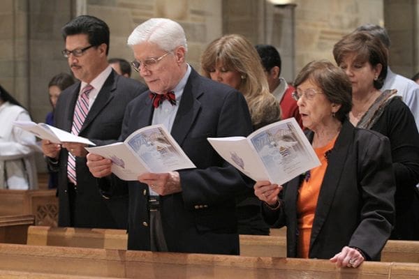 Dr. Carl Hug, upper pew, left, an anesthesiologist and intensive care doctor at Emory University Hospital, Atlanta, and his wife Marilyn join the congregation in singing the processional hymn during the first White Mass, Oct. 17, at the Cathedral of Christ the King, Atlanta. Photo By Michael Alexander