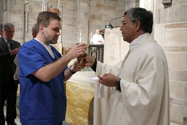 Michael Szczurek, left, a first year respiratory therapy student at Atlanta's Georgia State University, receives the blood of Christ from Father Balappa Selvaraj, chief advocate in the archdiocese's Metropolitan Tribunal. Photo By Michael Alexander